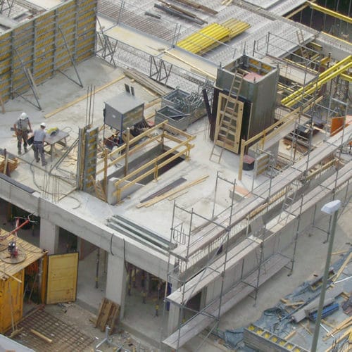 Bauarbeiten am Siegbogen: Bauarbeiter in Aktion auf einer Baustelle mit Gerüsten und Materialien.